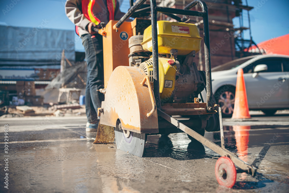 A worker pushing a concrete cutting machine